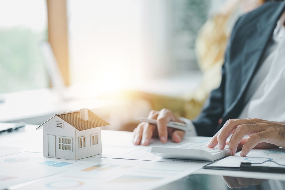 estate agent using calculator calculate for contract to buy or sell house, mortgage loan or home insurance in the office.